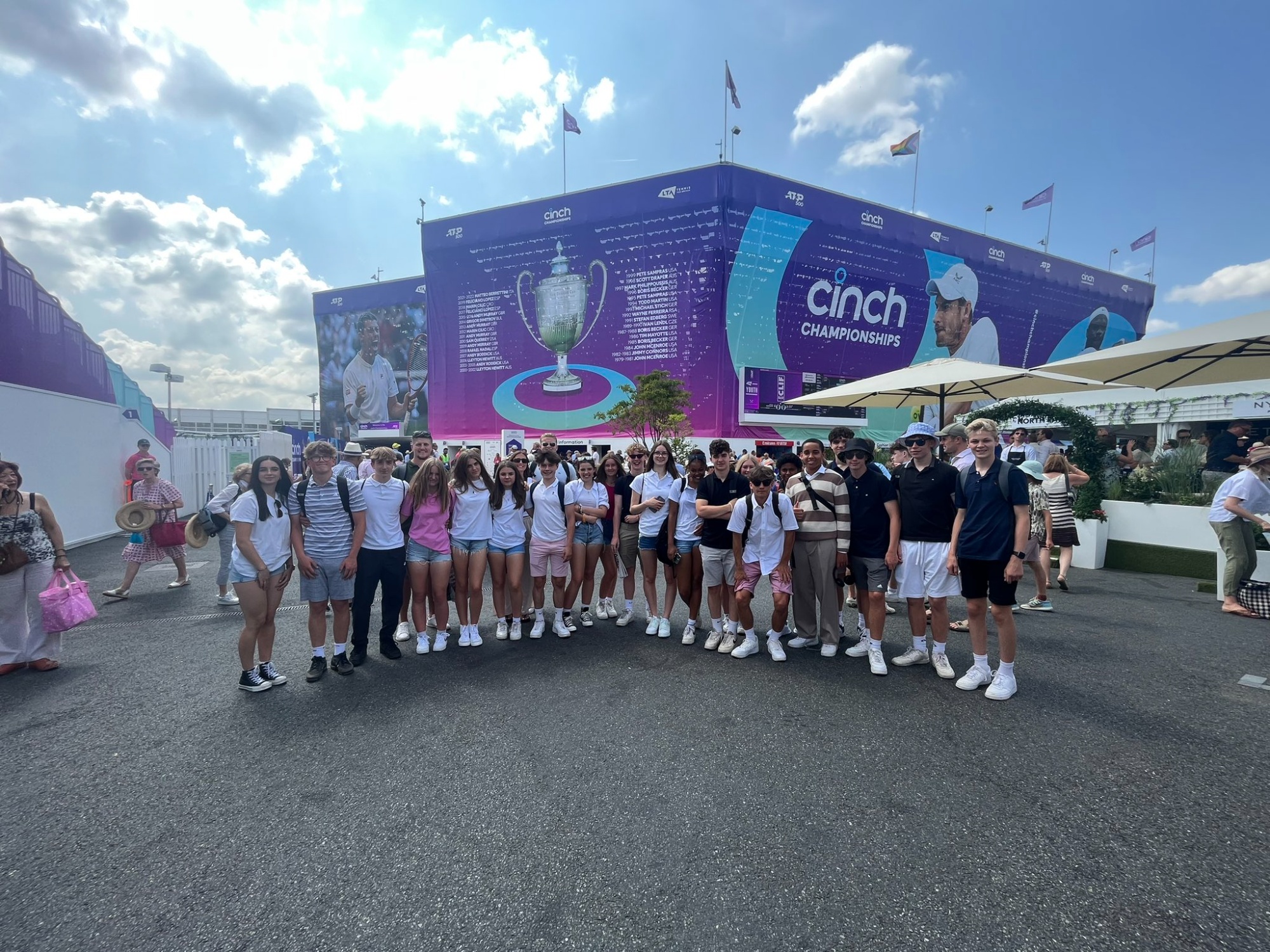 Group photograph of students and staff outside the Queen's tennis stadium 